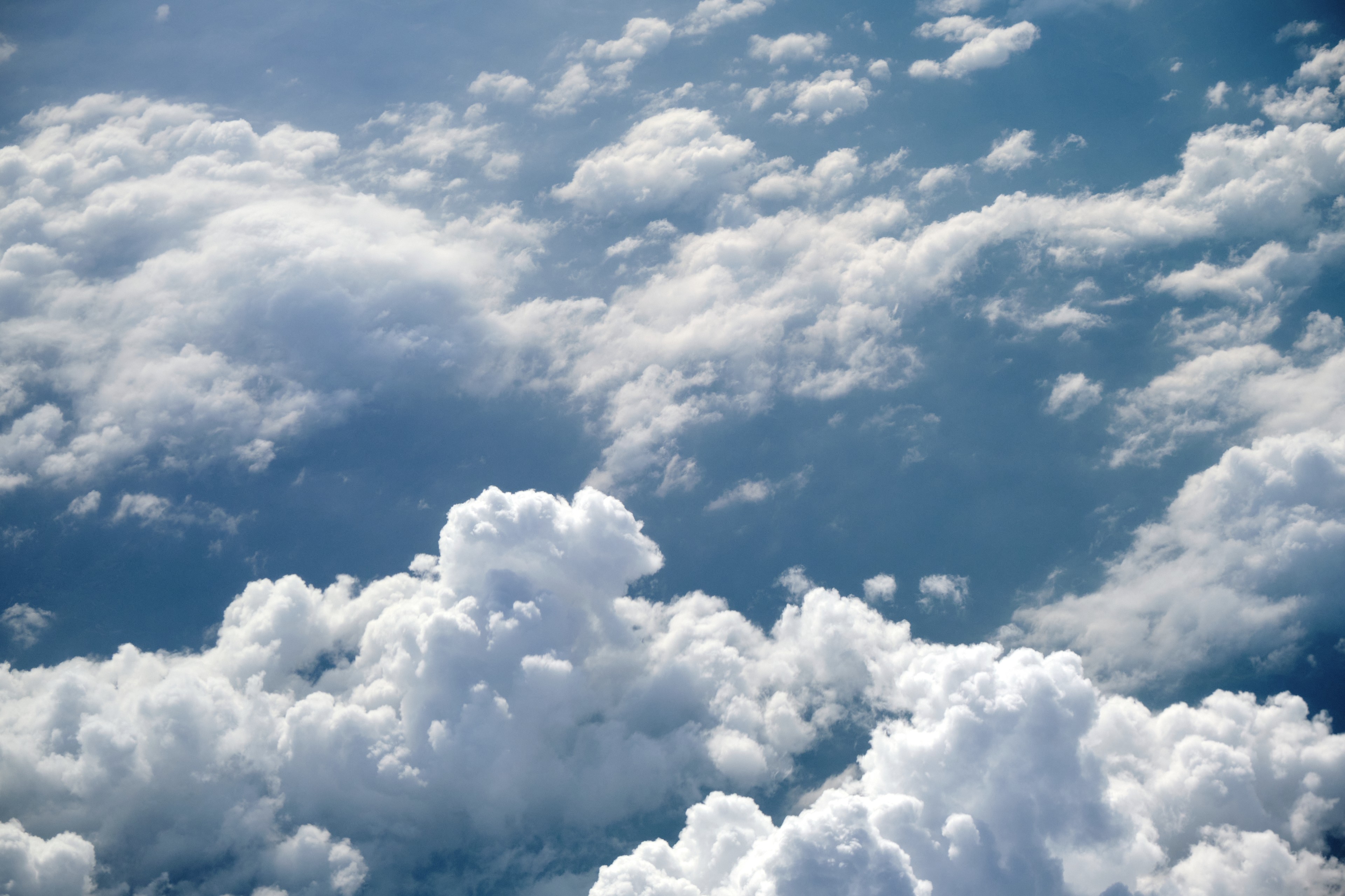 White cumulus clouds filling a blue sky, viewed from above
