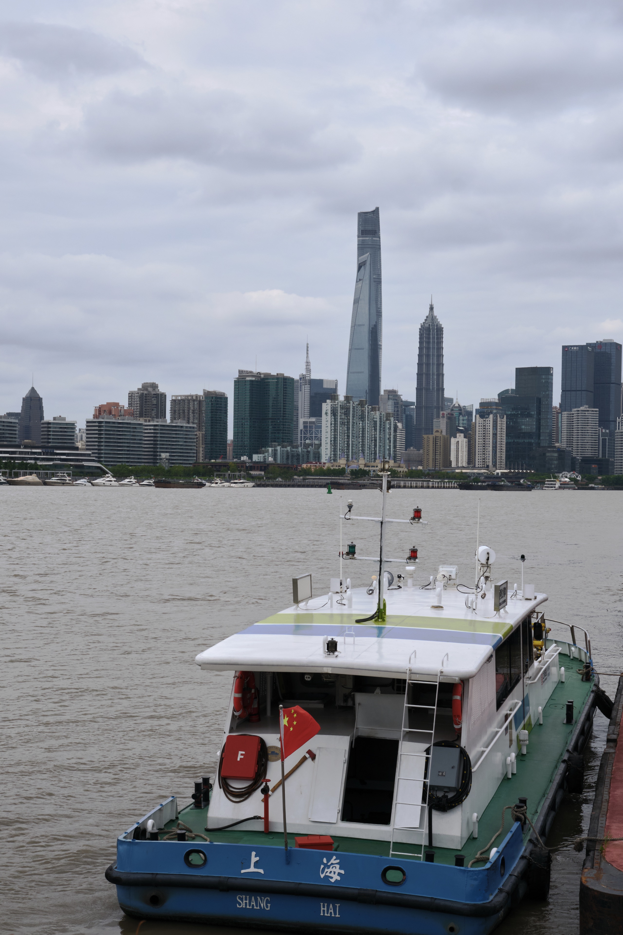 Blue boat on river, Shanghai skyline, cloudy sky