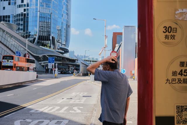 Man at bus stop, city skyline in background