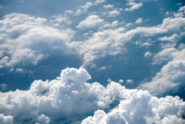 White cumulus clouds filling a blue sky, viewed from above