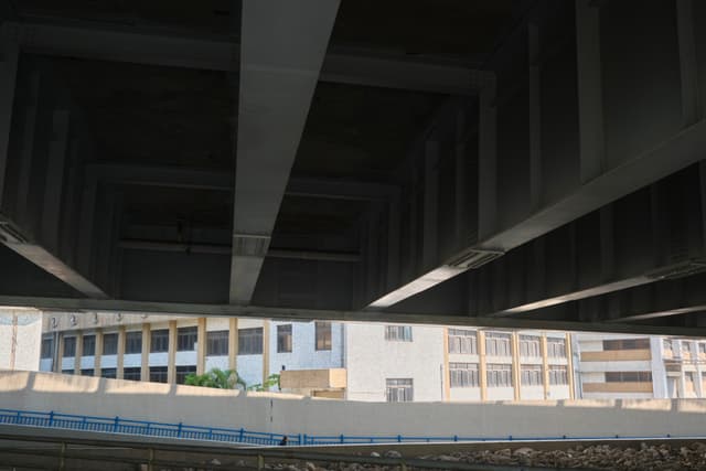 Looking up from under a bridge; view of the bridge's structure and buildings in the distance