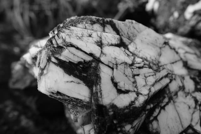 Monochrome close-up of a fractured rock surface with jagged black and white patterns