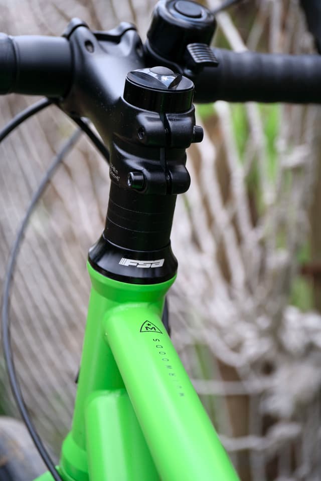 Close-up of a bright green bicycle frame with black handlebars and stem